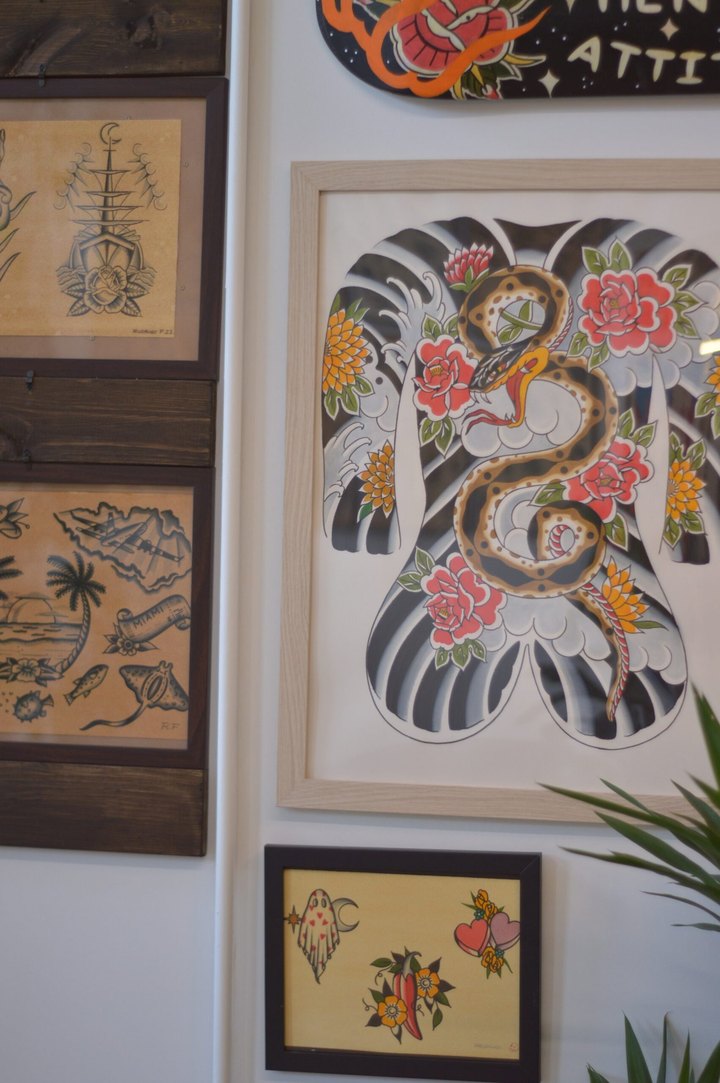 A wall of framed flash at La Rosa, including a Japanese snake and roses bodysuit painting.